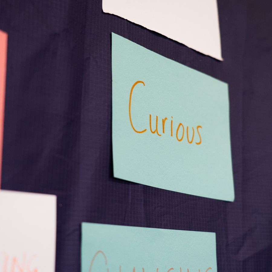 A wall of post-it notes. One is highlighted with the word: Curious. 