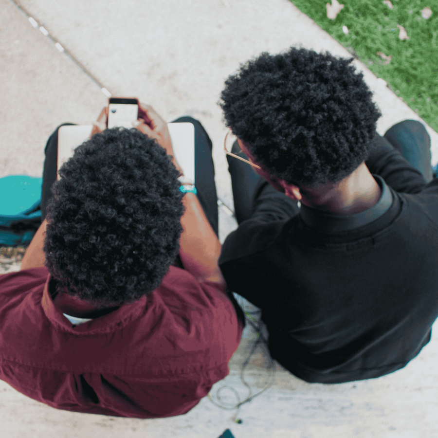 Overhead of 2 young people sat down and talking. 