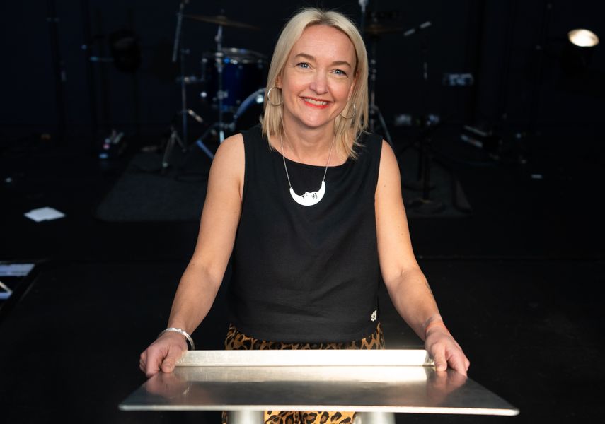 A professional woman with blonde hair stood at a podium.